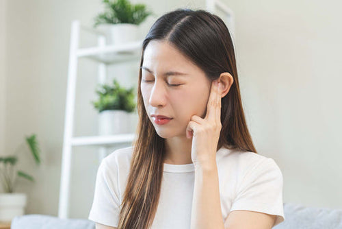 A woman suffering from ear pain from allergies