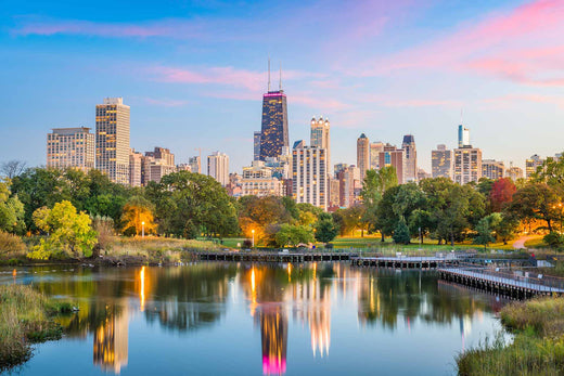 Chicago, Illinois skyline at sunset reflected in a Lincoln Park pond, framed by autumn trees