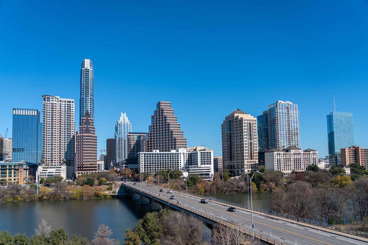 Austin, Texas skyline with high-rise buildings behind a bridge over the river under a clear blue sky