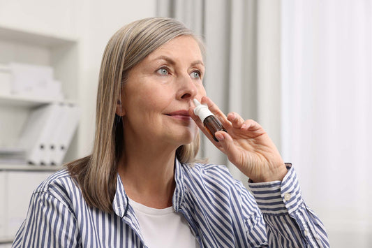 An old woman using nasal spray for sinusitis