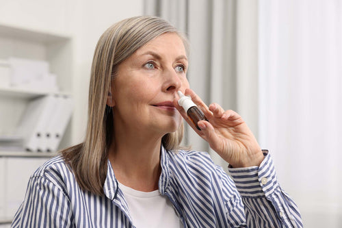 An old woman using nasal spray for sinusitis