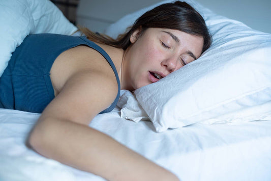 Person sleeping on their side in bed with mouth open, breathing through their mouth.